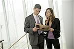 Businessman and businesswoman looking at financial newspaper