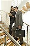 Businessman and businesswoman on staircase discussing over document