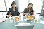 Businesswomen eating pizza at desk