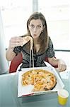 Businesswoman eating pizza at desk