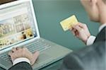 Businessman holding credit card at laptop