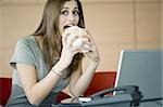 Businesswoman eating pita sandwich at desk