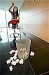 Businesswoman throwing paper into basket