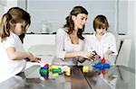 Young woman and boy and girl playing with building blocks