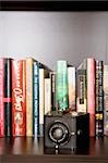 Close-up of a camera in front of books in a shelf