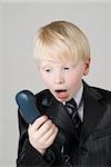 Close-up of a boy looking at a telephone receiver in shock