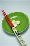 Close-up of three pills in a bowl with two chopsticks