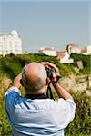 Rear view of a man filming with his home video camera, Biarritz, Basque Country, Pyrenees-Atlantiques, Aquitaine, France