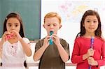 Écolier avec deux écolières jouant des flûtes dans une salle de classe