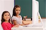 Porträt von zwei SchülerInnen mit Hilfe eines Computers in einem Klassenzimmer
