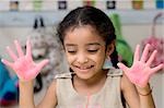 Close-up of a girl showing paint covered hands and smiling