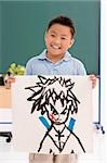 Portrait of a schoolboy showing his drawing and smiling