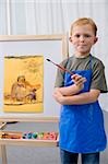Portrait d'un écolier tenant un pinceau, debout dans une classe d'art