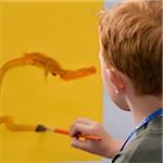 Rear view of a schoolboy painting in an art class