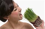 Close-up of a young woman trying to eat wheatgrass