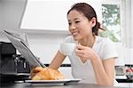 Young woman reading a newspaper and drinking tea