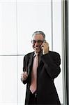 Businessman talking on a mobile phone and smiling in the waiting room of an airport