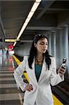 Businesswoman text messaging on a mobile phone at a subway station