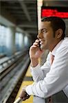 Side profile of a businessman talking on a mobile phone at a subway station