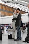 Side profile of a businessman and a businesswoman hugging each other at an airport