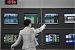 Rear view of a businesswoman pointing at an arrival departure board in an airport