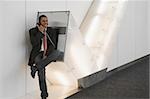 Businessman talking on a pay phone at an airport and smiling