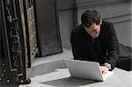 Businessman sitting on steps and using a laptop