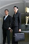 Portrait of a businesswoman carrying a briefcase with a businessman standing behind her