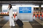 Side profile of a businesswoman talking on a mobile phone and pulling her luggage at a subway station