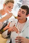 Young woman feeding food to a young man