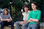 Portrait of two teenage boys sitting with a young man and smiling