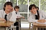 Adolescente et un jeune homme assis dans une salle de classe et souriant