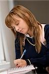 Close-up of a teenage girl writing in a spiral notebook