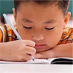 Close-up of a schoolboy writing on a notebook with a pencil