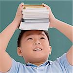 Gros plan d'un écolier tenant des livres sur sa tête