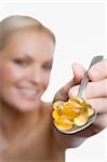 Nahaufnahme einer jungen Frau in einem Löffel Vitaminpillen zeigen