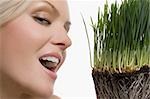 Close-up of a young woman smiling with wheatgrass in front of her face