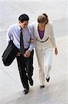 Businessman and a businesswoman moving up on steps with their arm in arm