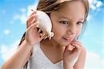 Close-up of a girl holding a seashell close to her ear