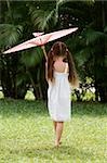 Rear view of a girl walking in a park with an umbrella