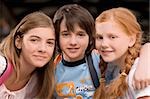 Portrait of a schoolboy with two schoolgirls smiling together