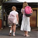 Vue arrière de deux écolières transportant des sacs d'école et de la marche