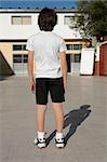 Rear view of a schoolboy standing in front of a school building