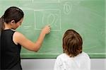 Rear view of a female teacher teaching a schoolboy in a classroom