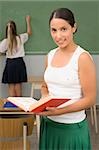Gros plan d'une enseignante, tenant un livre avec une écolière écrit sur une ardoise en arrière-plan