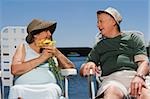 Altes Paar sitzt am See und schauen einander an