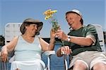 Senior homme donnant des fleurs à une femme senior et souriant