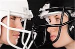 Close-up of two businesswomen wearing football helmets and looking at each other