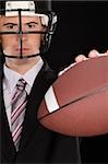 Portrait d'un homme d'affaires portant un casque de football et en maintenant un joueur de football américain