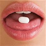 Close-up of a pill on a young woman's tongue